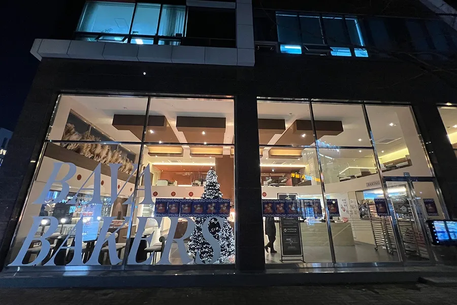 야간 조명이 켜진 카페 정면 파사드 통유리 안전필름 시공 완료
