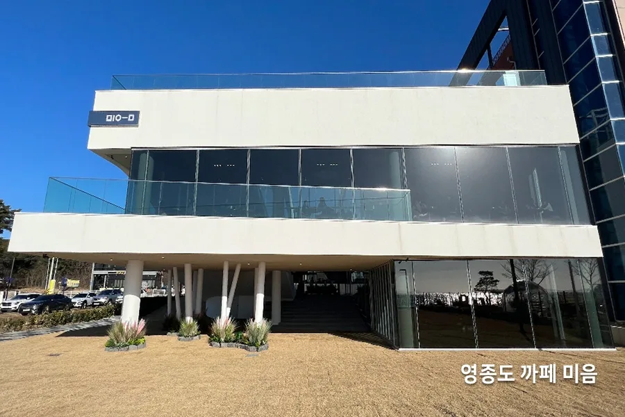 두 명의 작업자가 나란히 사다리에 올라 파노라마 통유리 상단을 작업하는 모습