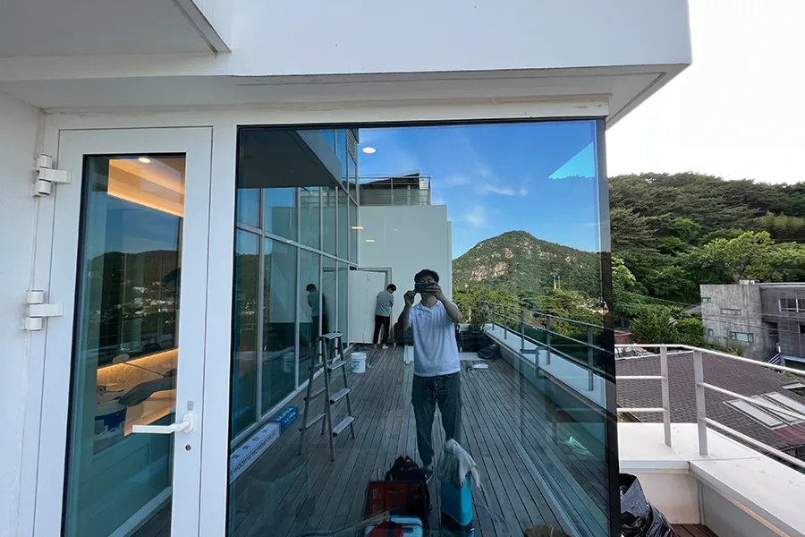 옥상 테라스 유리 도어와 창, 저녁 조명이 켜진 실내가 함께 보이는 모습